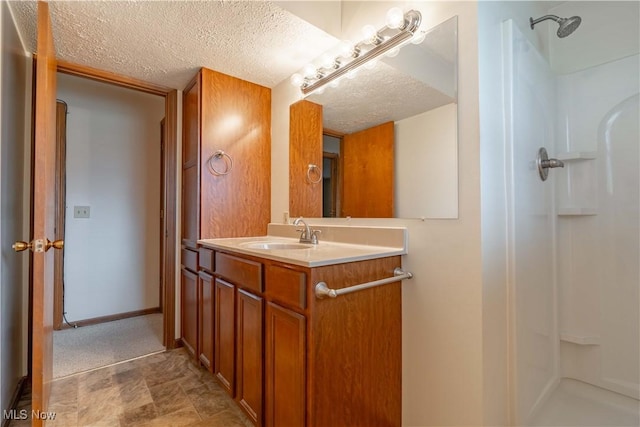 bathroom featuring baseboards, a shower, a textured ceiling, and vanity