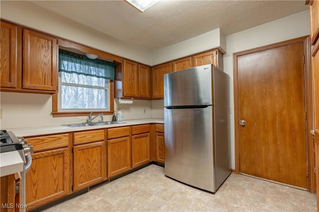 kitchen featuring appliances with stainless steel finishes, brown cabinets, a sink, and light countertops