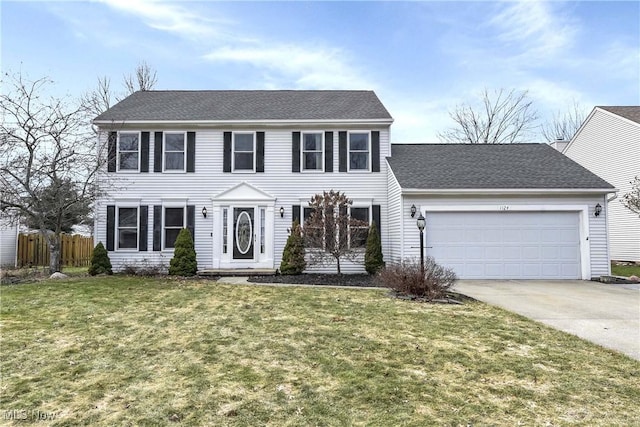 colonial-style house featuring driveway, a garage, a shingled roof, fence, and a front lawn