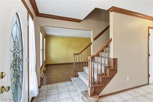 entryway featuring stairway, baseboards, crown molding, and tile patterned floors