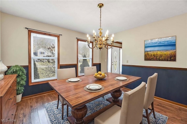 dining space with a notable chandelier, baseboards, and wood finished floors