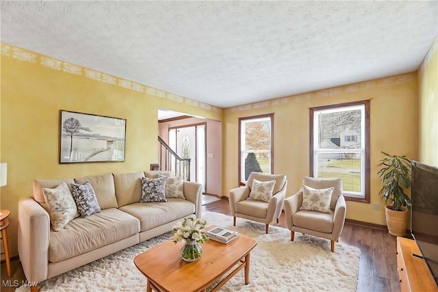 living area with a textured ceiling, baseboards, and wood finished floors