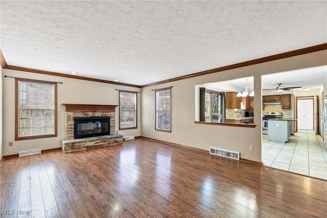 unfurnished living room with light wood-type flooring, visible vents, and a stone fireplace