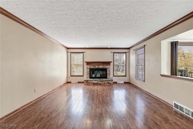 unfurnished living room featuring wood-type flooring, visible vents, a stone fireplace, and a textured ceiling