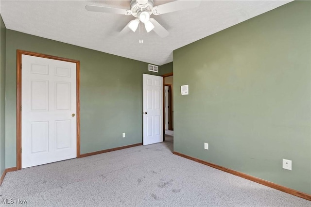 unfurnished bedroom with a textured ceiling, carpet floors, a ceiling fan, visible vents, and baseboards