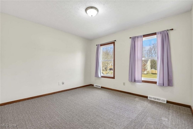 carpeted spare room featuring baseboards, visible vents, and a textured ceiling