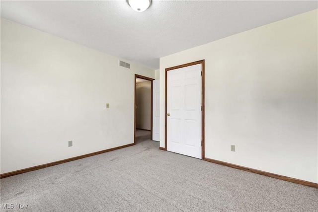 unfurnished bedroom with carpet floors, visible vents, a textured ceiling, and baseboards