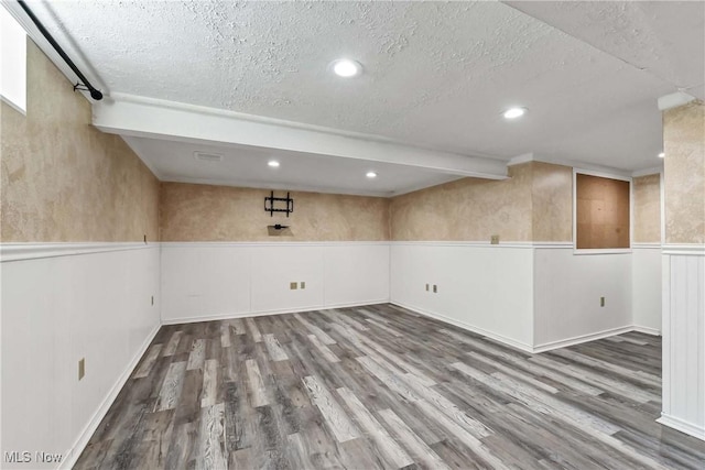 basement featuring a textured ceiling, wainscoting, wood finished floors, and recessed lighting