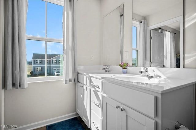 bathroom featuring double vanity, baseboards, and a sink