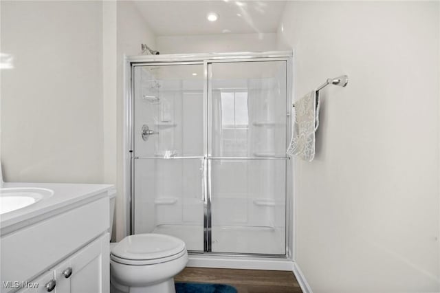 full bathroom featuring toilet, a stall shower, wood finished floors, and vanity