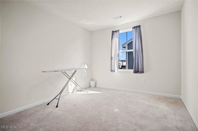 carpeted spare room featuring visible vents and baseboards