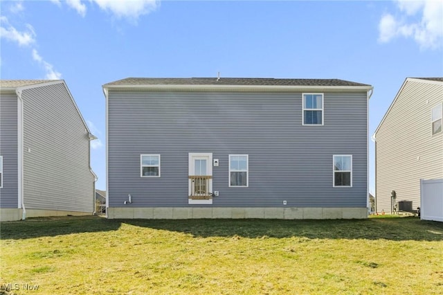 rear view of property featuring central air condition unit and a lawn