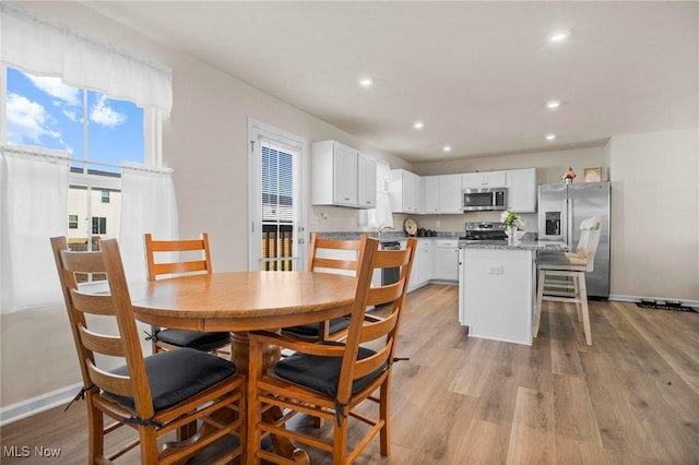 dining space featuring light wood finished floors, baseboards, and recessed lighting