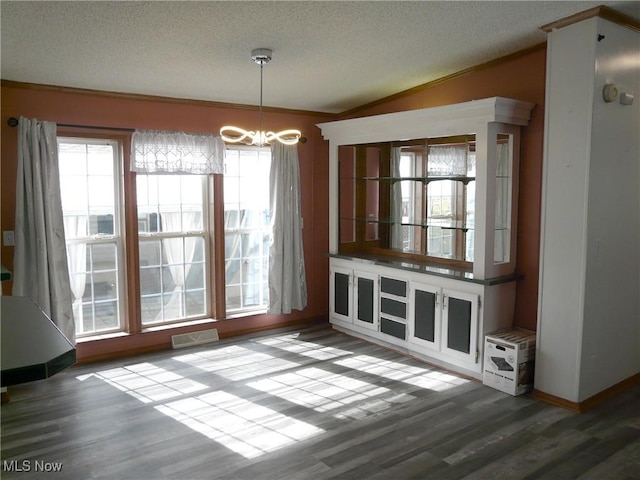 unfurnished dining area featuring plenty of natural light, visible vents, vaulted ceiling, and a textured ceiling