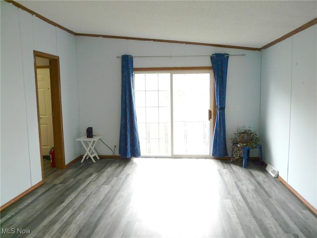 empty room with visible vents, crown molding, and wood finished floors