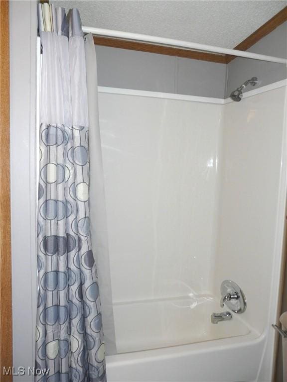 full bathroom with shower / bath combination with curtain and a textured ceiling