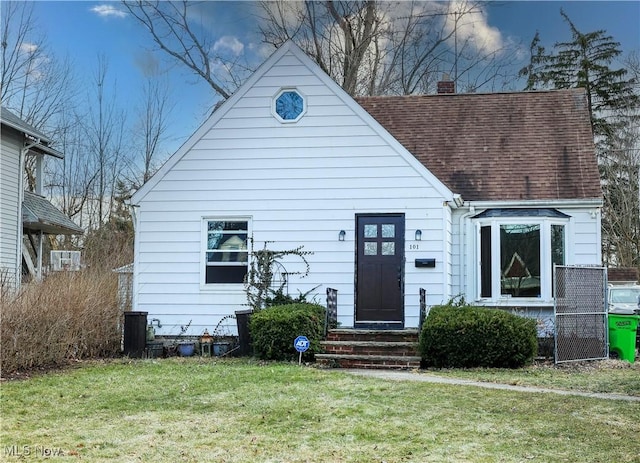 view of front of home with a shingled roof, a chimney, and a front lawn