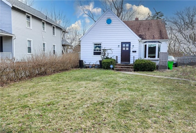 view of front of property with a shingled roof, a chimney, and a front yard