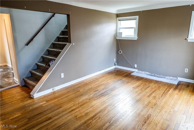 below grade area featuring wood-type flooring, baseboards, and stairs