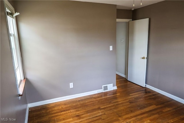 unfurnished room featuring wood finished floors, visible vents, and baseboards