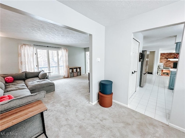 living area featuring light tile patterned floors, baseboards, a textured ceiling, and light colored carpet