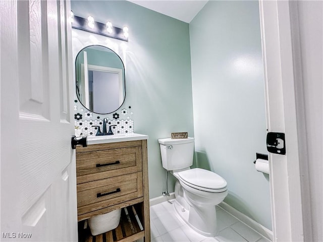 bathroom with toilet, tile patterned floors, baseboards, and vanity