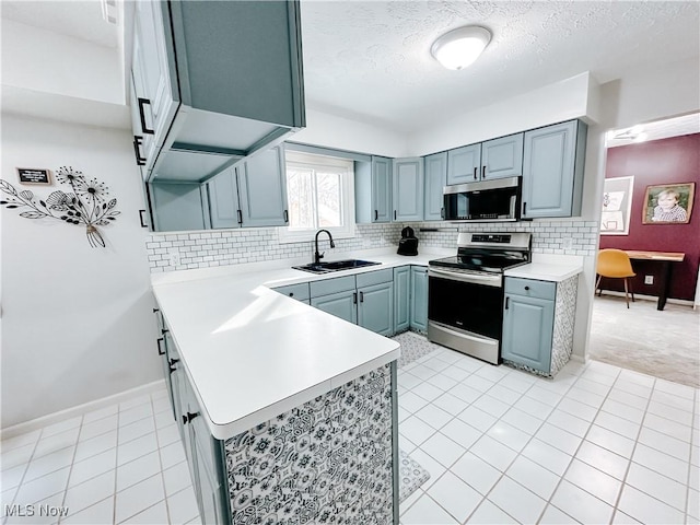 kitchen featuring stainless steel appliances, a sink, light countertops, and decorative backsplash