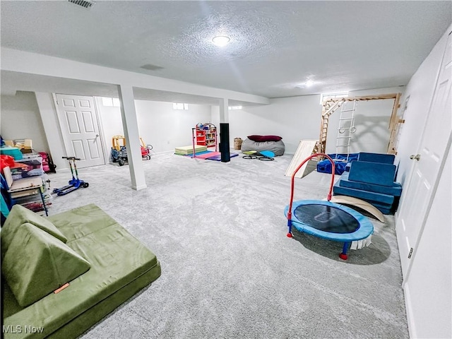 playroom with carpet, visible vents, and a textured ceiling