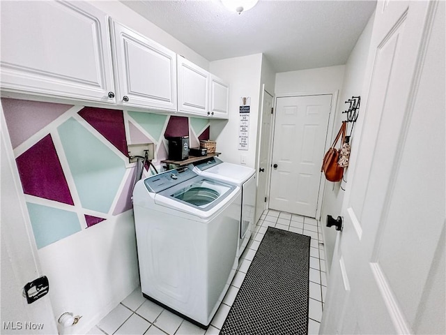 washroom with light tile patterned floors, washing machine and dryer, and cabinet space