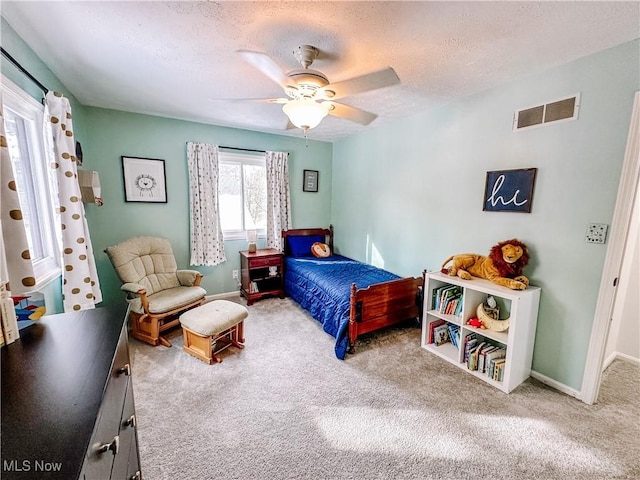 carpeted bedroom featuring baseboards, ceiling fan, visible vents, and a textured ceiling