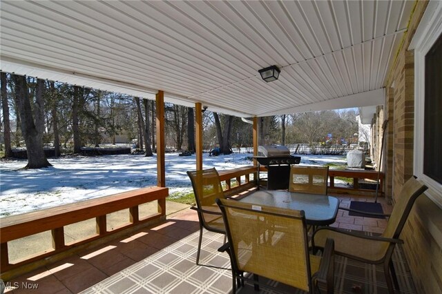 snow covered patio featuring outdoor dining space and area for grilling