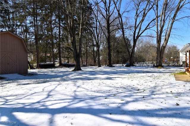 yard covered in snow with an outbuilding, a detached garage, and a barn