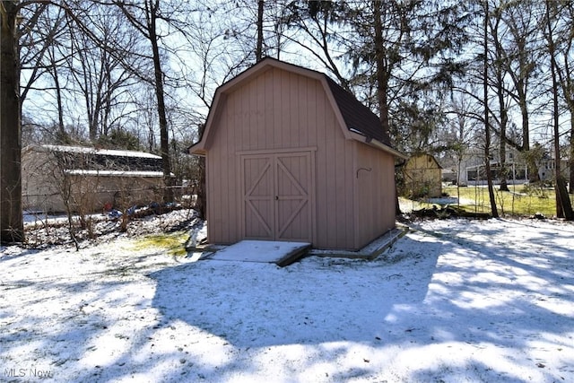 snow covered structure featuring a storage unit and an outdoor structure