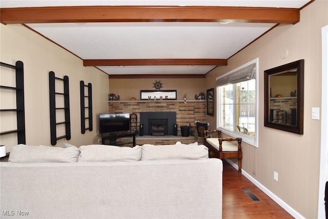 living room with wood finished floors, visible vents, baseboards, a brick fireplace, and beam ceiling