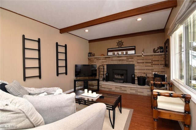 living room with ornamental molding, a fireplace, beamed ceiling, and wood finished floors