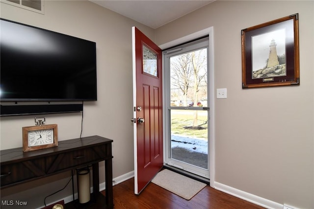 foyer entrance with dark wood-style floors, baseboards, and visible vents