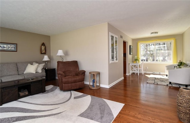 living room with wood finished floors, visible vents, and baseboards