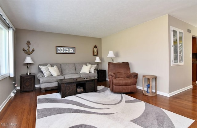 living room with wood finished floors, visible vents, and baseboards