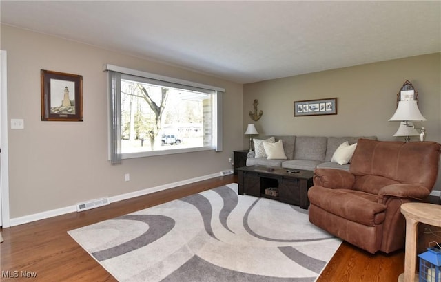 living area featuring wood finished floors, visible vents, and baseboards