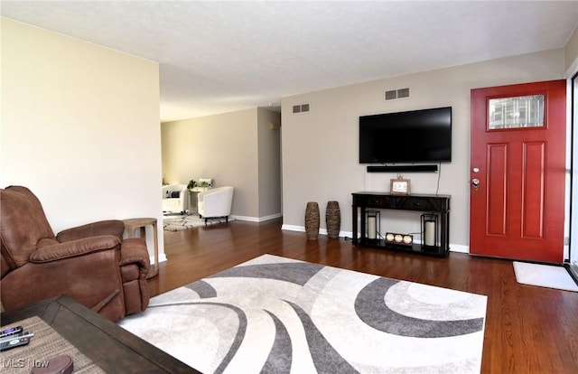 living room featuring baseboards, visible vents, and wood finished floors