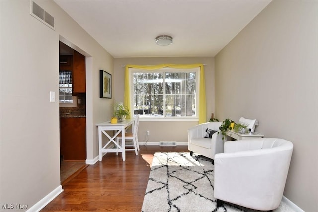 living area with baseboards, visible vents, and wood finished floors