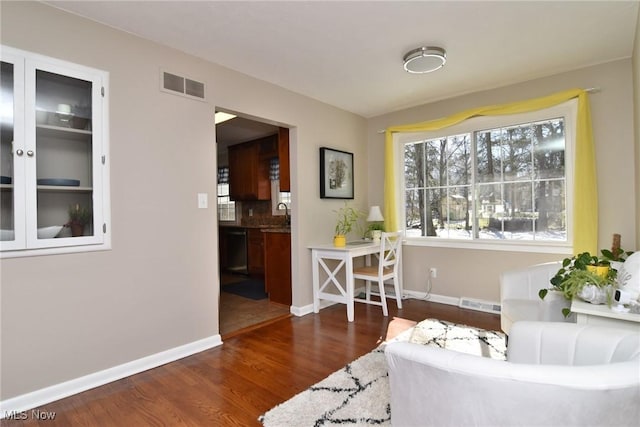 sitting room with visible vents, baseboards, and wood finished floors