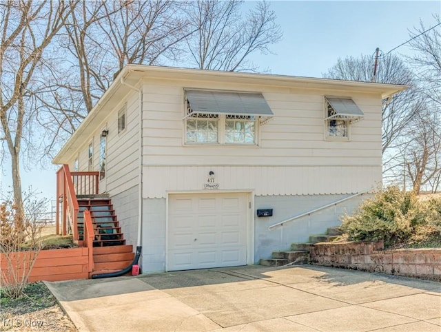 view of side of home with a garage, driveway, and stairs