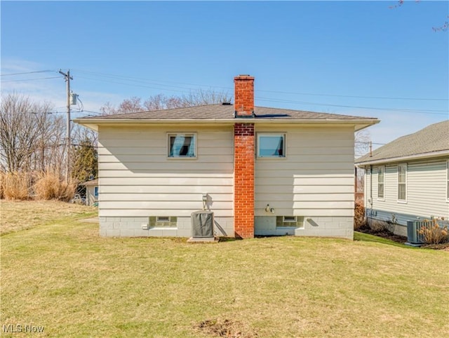 back of house with a yard, a chimney, and cooling unit