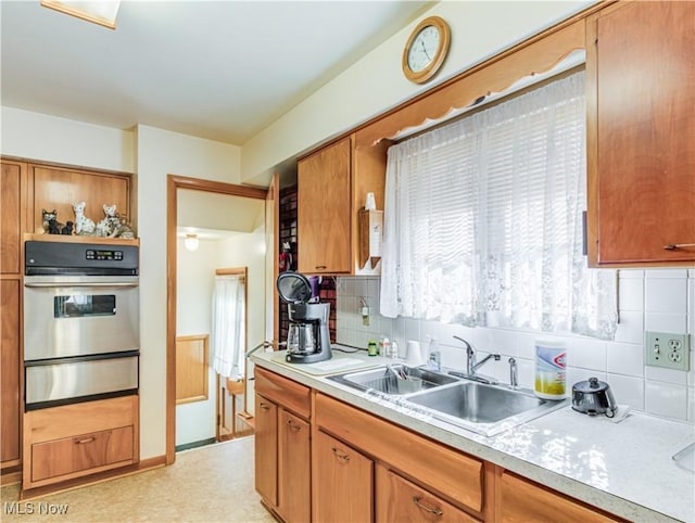 kitchen featuring light countertops, light floors, stainless steel oven, a sink, and a warming drawer