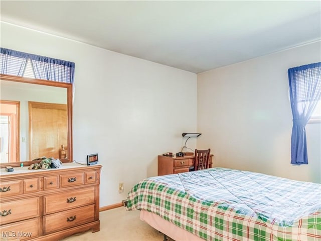 bedroom featuring light carpet and baseboards