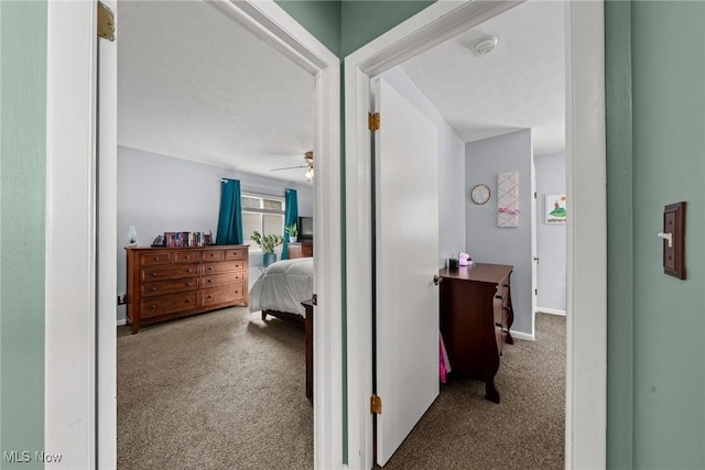 hallway featuring carpet and baseboards