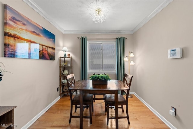 dining area featuring light wood-style flooring, ornamental molding, and baseboards