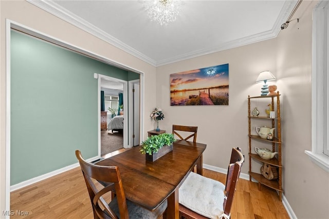 dining space featuring crown molding, light wood-style flooring, and baseboards