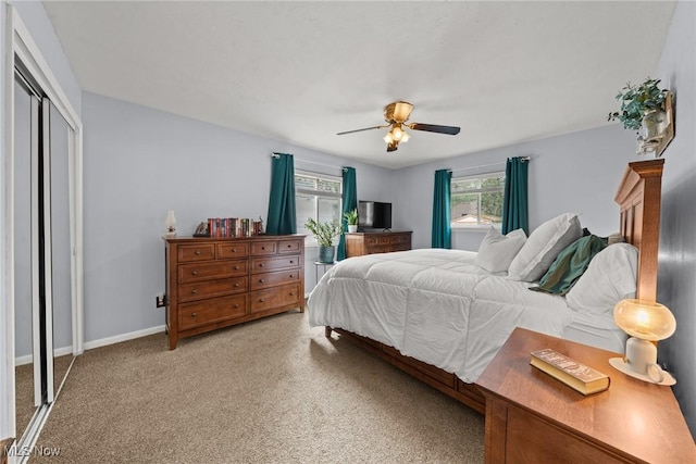 bedroom with a closet, light colored carpet, ceiling fan, and baseboards